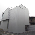 シルバーのガルバリウム鋼板に覆われ、窓が1つもない正面側の外観©MBS